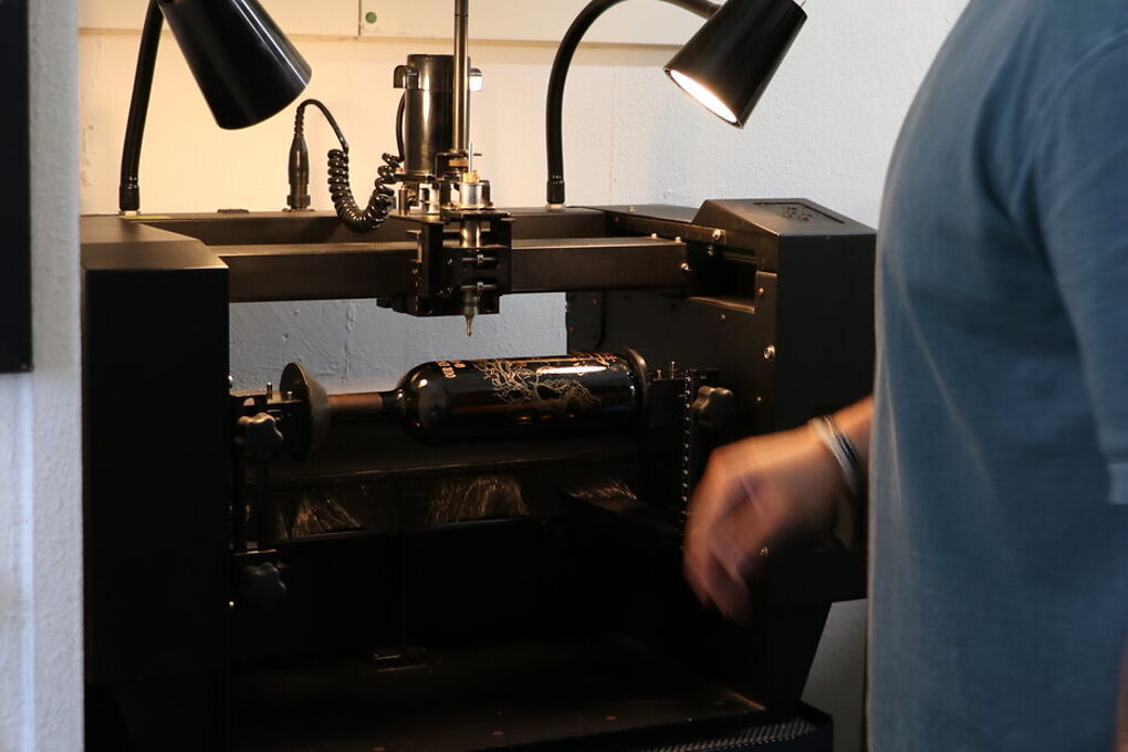 Rotary bottle engraving station engraving a bottle in the shop